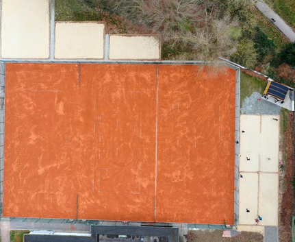 Luftaufnahme mehrerer roter Tonplätze auf Sportanlage neben Sandflächen