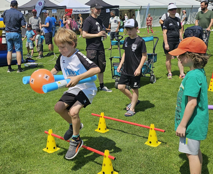 Junge springt Hindernis mit Poolnudeln bei Sport-Kids-Olympiade