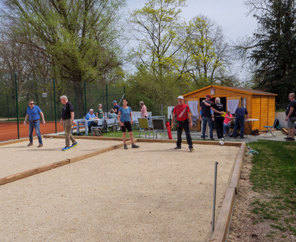 Teilnehmer spielen Boule beim Memory-Turnier neben Holzhütte