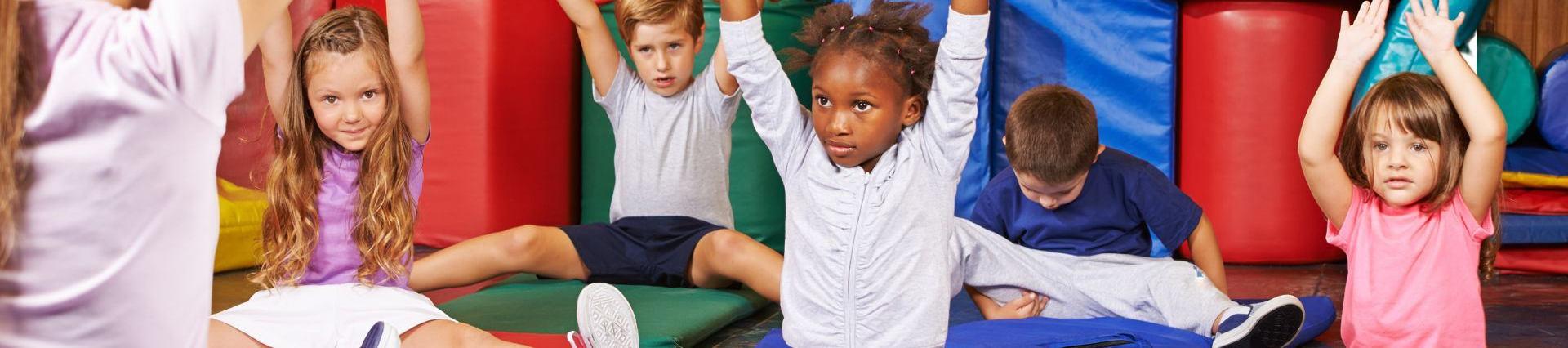 Vorschulkinder auf Matten beim gemeinsamen Turnen mit Lehrkraft