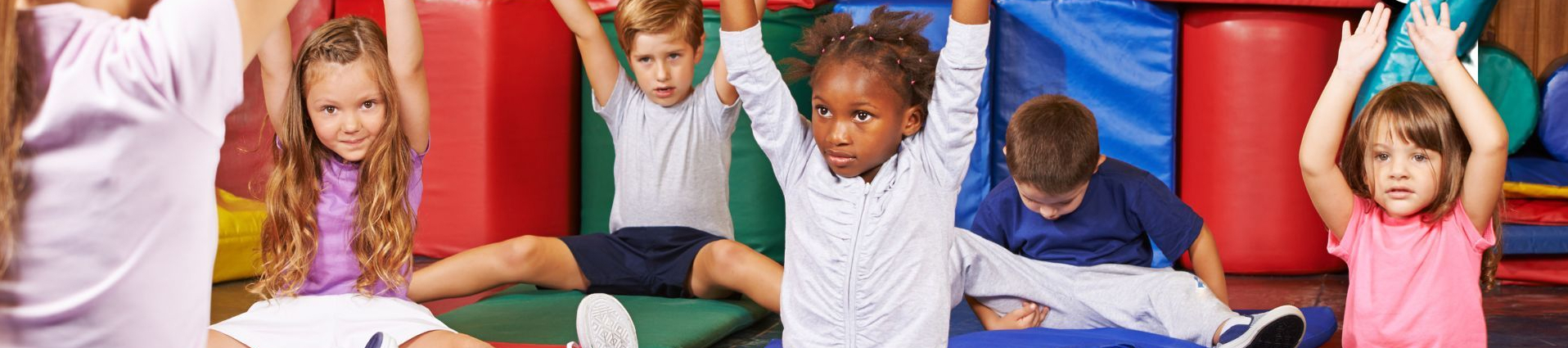 Vorschulkinder auf Matten beim gemeinsamen Turnen mit Lehrkraft