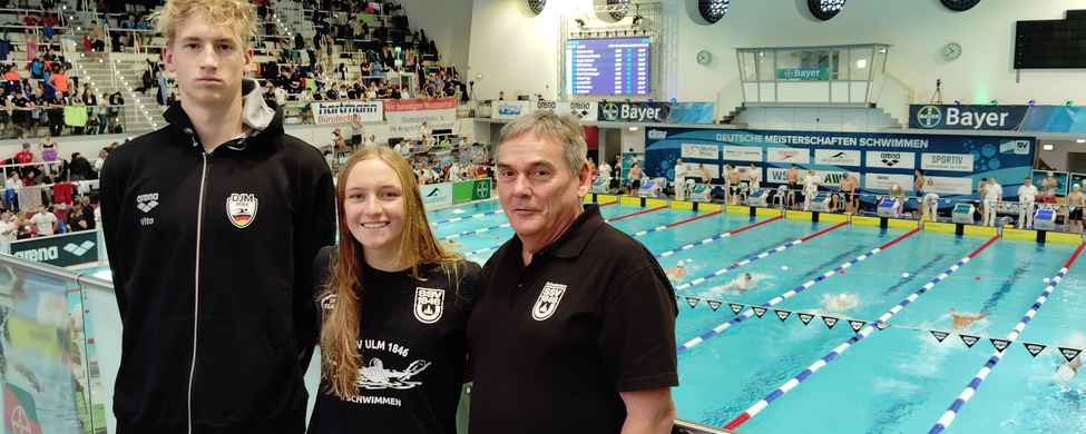Drei Personen in SSV Ulm 1846 Shirts vor Banner Deutsche Meisterschaften Schwimmen
