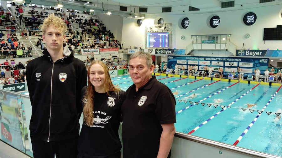 Drei Personen in SSV Ulm 1846 Shirts vor Banner Deutsche Meisterschaften Schwimmen