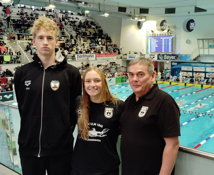 Drei Personen in SSV Ulm 1846 Shirts vor Banner Deutsche Meisterschaften Schwimmen