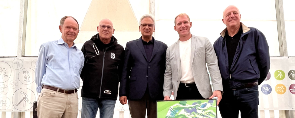 Fünf Personen auf einer Bühne mit gerahmtem München 1972 Plakat