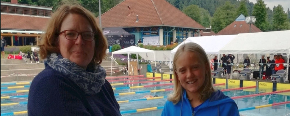 Jugendlicher Schwimmer erhält Urkunden durch Handschlag am Wettkampfbecken