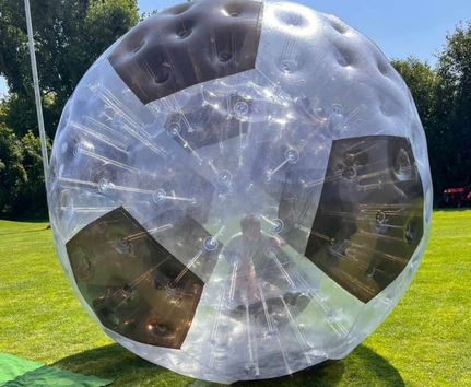 Transparent soccer-shaped zorb with person inside on grass