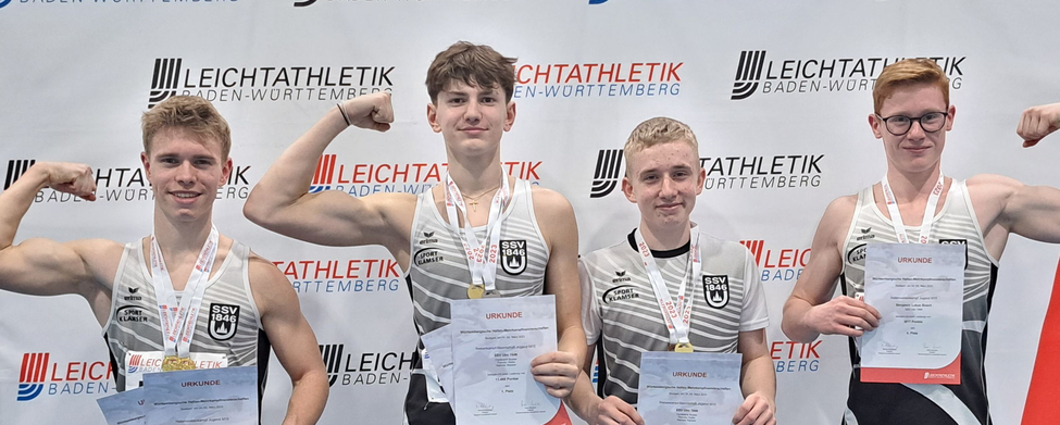 Vier jugendliche Athleten mit Medaillen und Urkunden vor Leichtathletik Baden-Württemberg Banner
