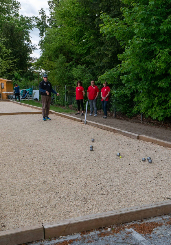 Personen spielen Boule auf Kiesbahnen mit Metallkugeln und kleinem Zielball