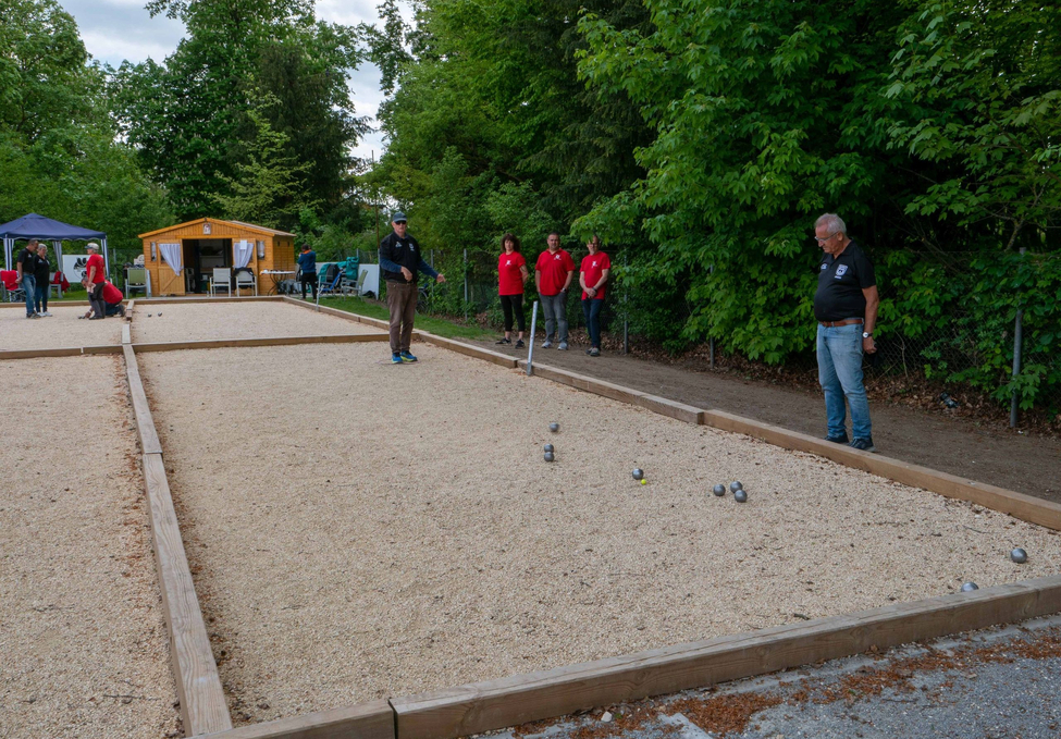 Personen spielen Boule auf Kiesbahnen mit Metallkugeln und kleinem Zielball