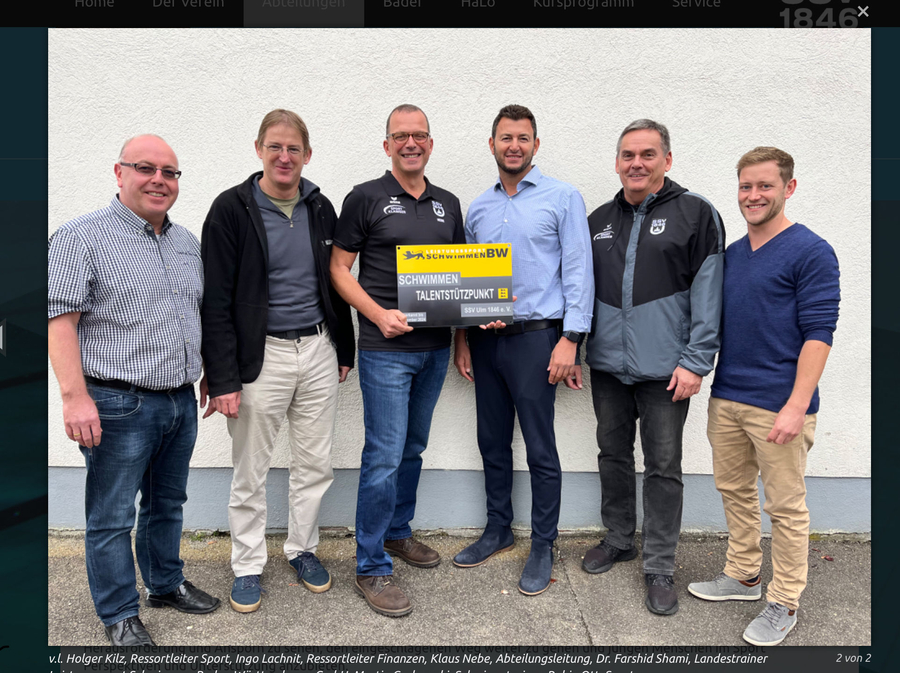Sechs Männer halten Tafel mit Aufschrift Schwimmen Talentstützpunkt vor Wand
