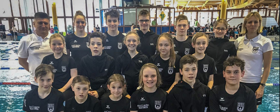 Jugendliche Schwimmer und Trainer als Team neben Wettkampfbecken
