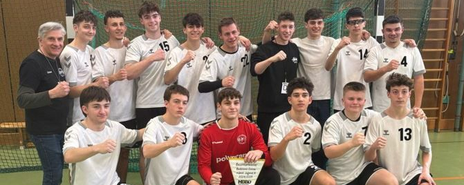 Jugendhandballmannschaft posiert vor Tor mit Wimpel und Fäusten