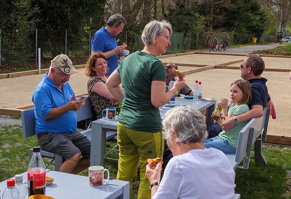 Mehrere Personen essen und trinken an Außentischen