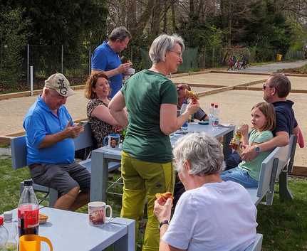 Mehrere Personen essen und trinken an Außentischen