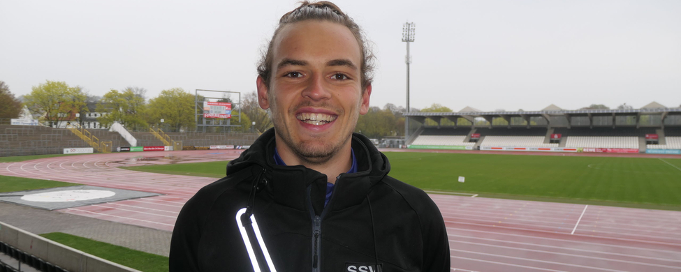 Junger Mann lächelnd vor Stadion mit SSV 1846 Jacke