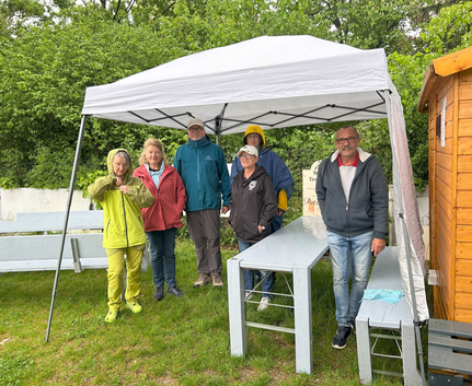 Sechs Personen unter Pavillon bei regnerischem Tag der offenen Tür