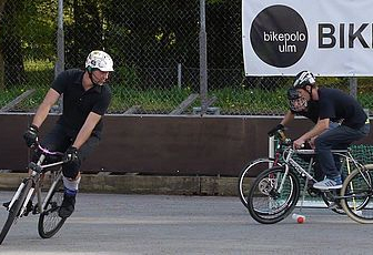 Vier helmtragende Spieler auf Fahrrädern beim Bikepolo Banner BIKEPOLO ULM