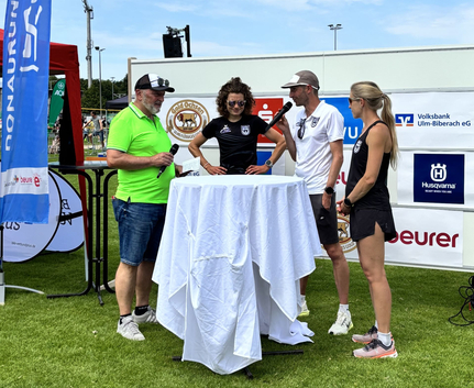 Vier Personen stehen an Stehtisch mit Mikrofonen beim Schwörsporttag
