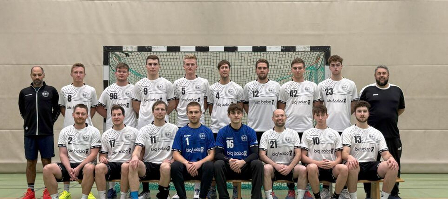 Handballmannschaft in weißen Trikots vor Tor