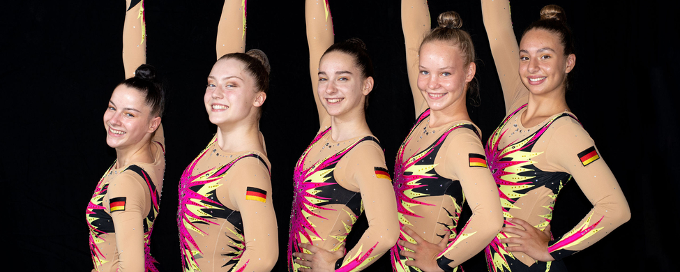 Fünf lächelnde Sport-Aerobic-Athletinnen mit gehobenen Armen und deutscher Flagge