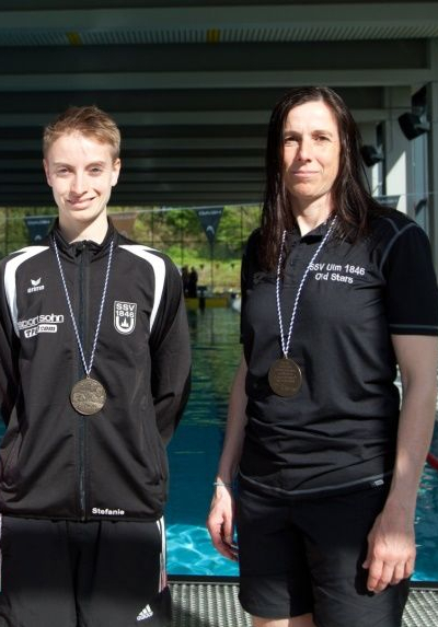 Vier Frauen mit Medaillen stehen vor Schwimmbecken