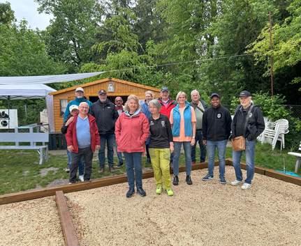 Gruppe von Boulespielern vor Vereinshütte bei regnerischem Wetter