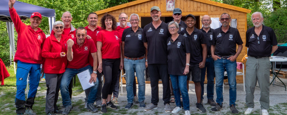 Gruppe von Erwachsenen in roten und schwarzen Teamshirts vor Holzhütte