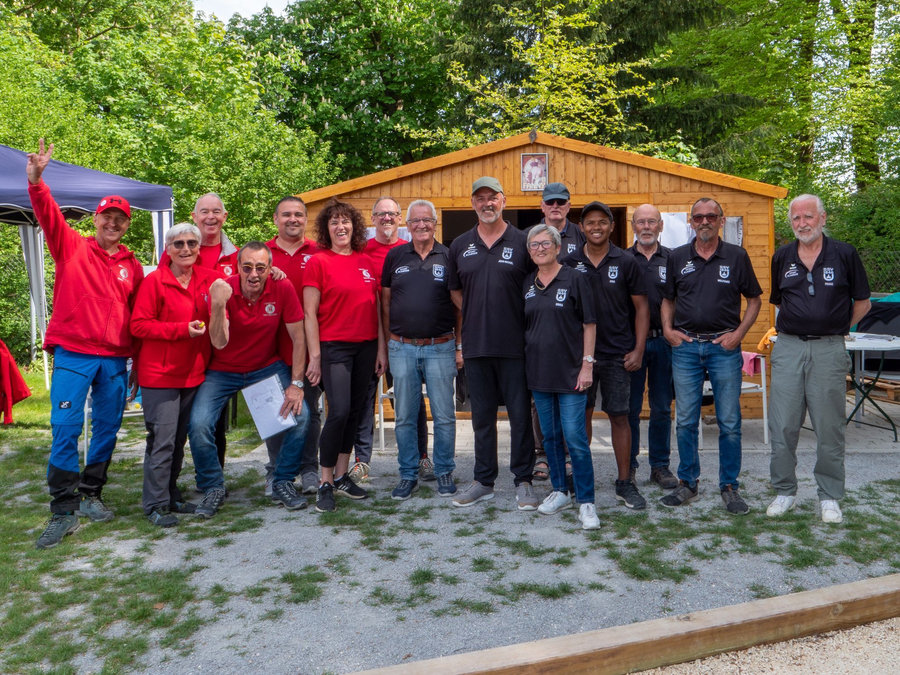 Gruppe von Erwachsenen in roten und schwarzen Teamshirts vor Holzhütte