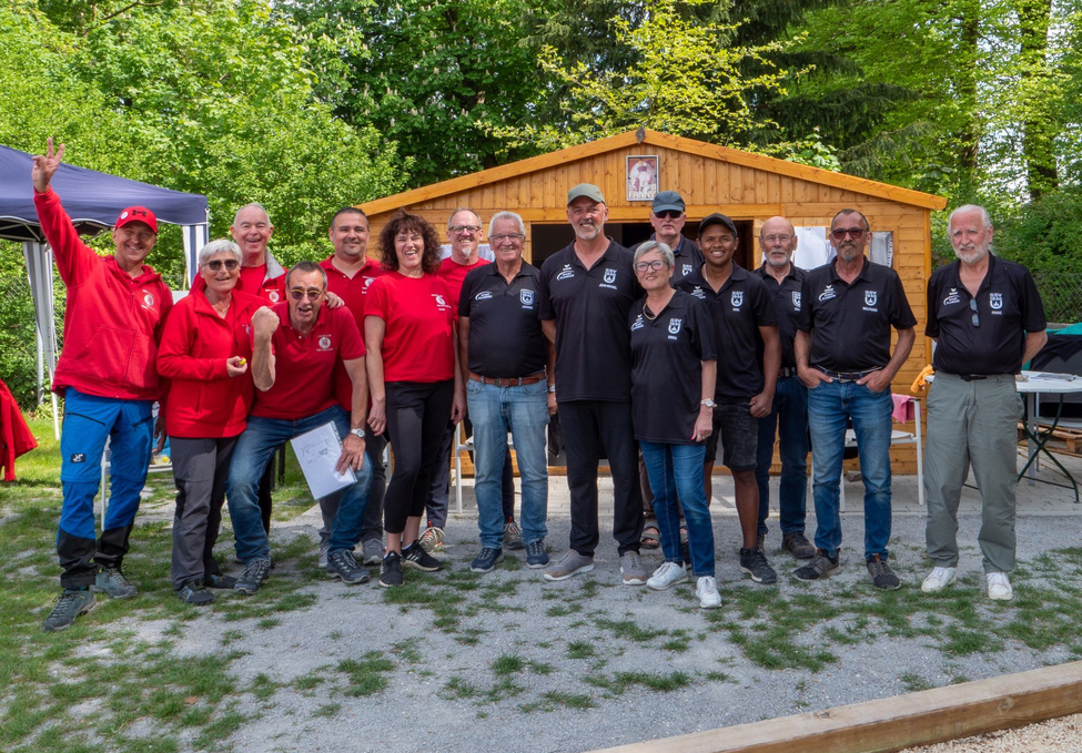 Gruppe von Erwachsenen in roten und schwarzen Teamshirts vor Holzhütte