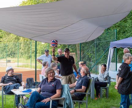 Gruppe beim Sonntagsturnier unter Sonnensegel, Mann hält Pokal mit Union Jack