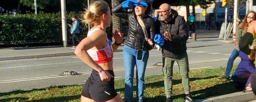 Läuferin im roten Trikot und grünen Schuhen läuft vorbei an jubelnden Zuschauern