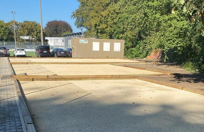 Gravel playing courts with wooden borders next to paved walkway