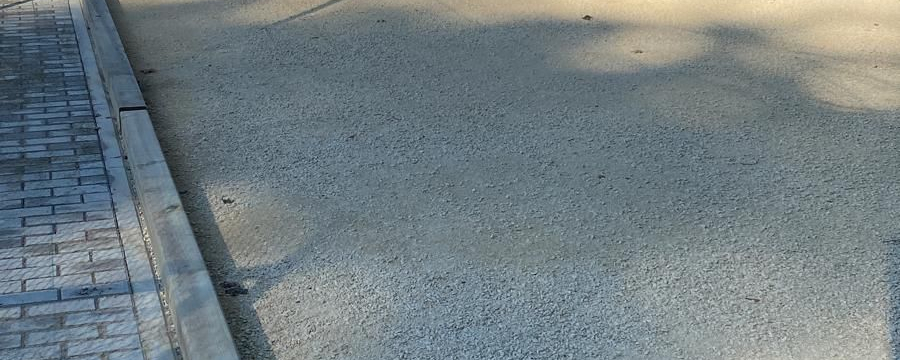 Gravel playing courts with wooden borders next to paved walkway