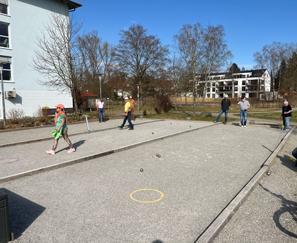 Mehrere Menschen spielen Boule auf sonnigen Sandbahnen beim Freundschaftsturnier in Krumbach