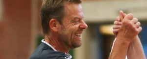 Lächelnder Tischtennisspieler in Sportshirt klatscht Hände mit Mitspieler in Turnhalle