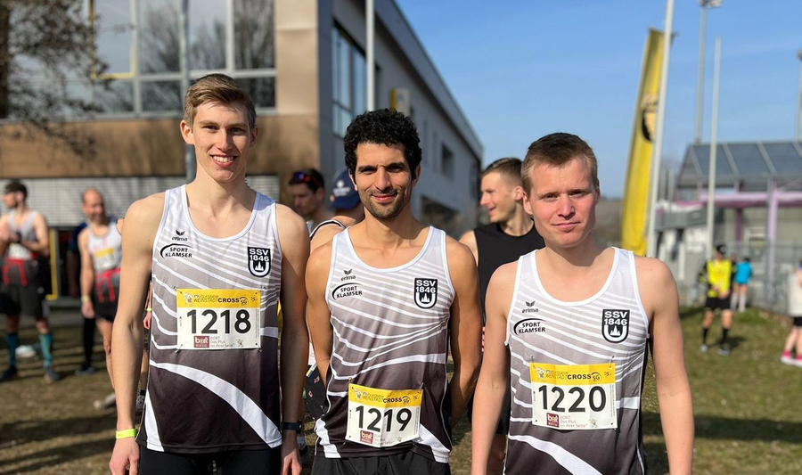 Drei Läufer in weißen Teamtrikots mit Startnummern 1218 1219 1220