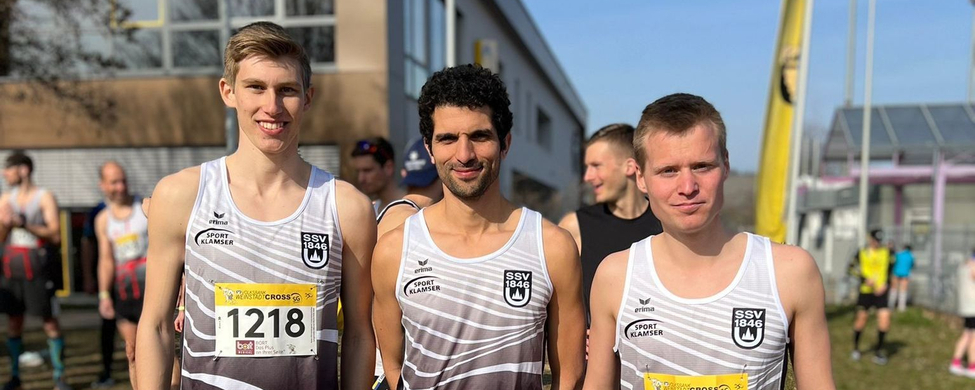 Drei Läufer in weißen Teamtrikots mit Startnummern 1218 1219 1220