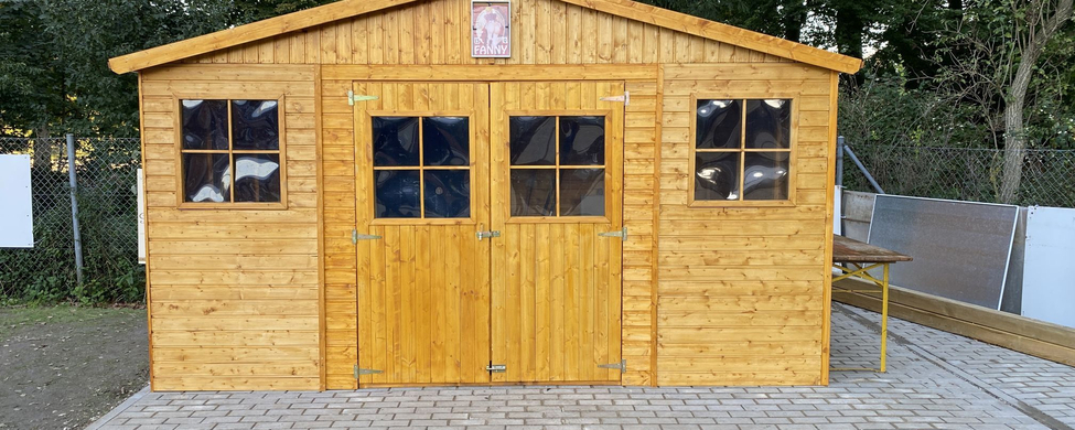 Holzschuppen mit Doppeltür und Seitenfenstern auf gepflastertem Untergrund