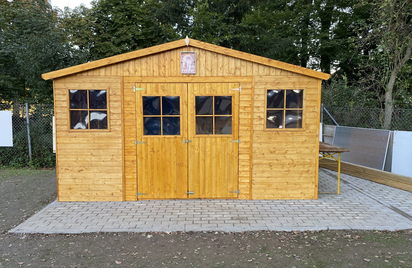Holzschuppen mit Doppeltür und Seitenfenstern auf gepflastertem Untergrund