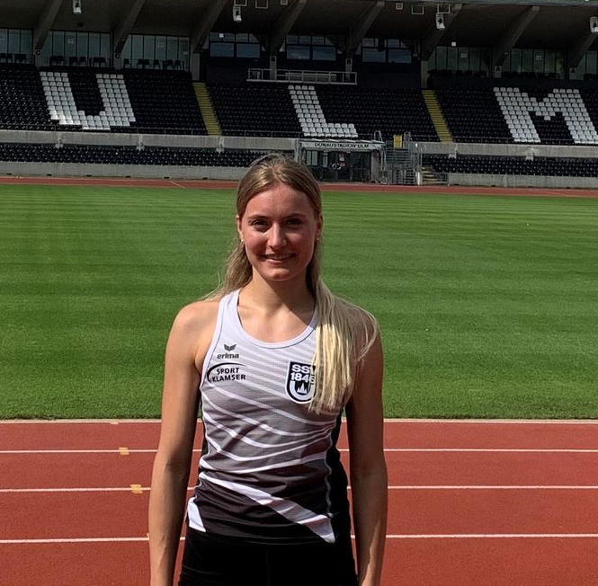 Athlete standing on red running track in front of stadium