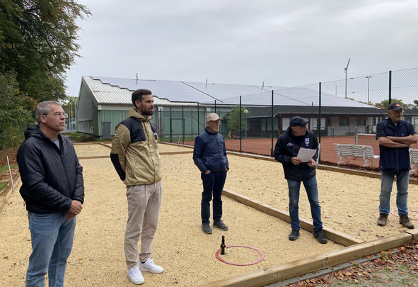 Fünf Personen stehen auf kiesigem Platz neben Gebäude mit Solarpanels