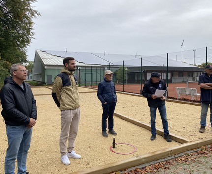 Fünf Personen stehen auf kiesigem Platz neben Gebäude mit Solarpanels