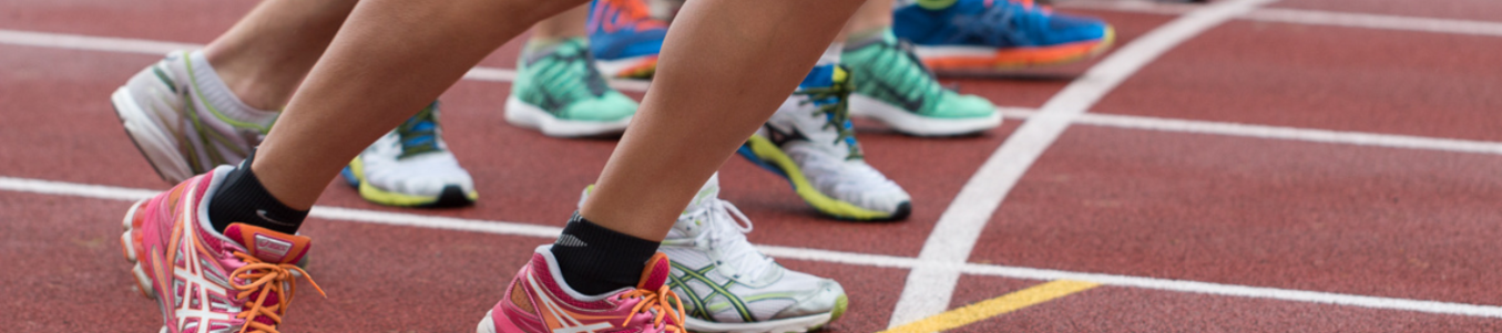 Mehrere Läufer mit bunten Sportschuhen an Startlinie