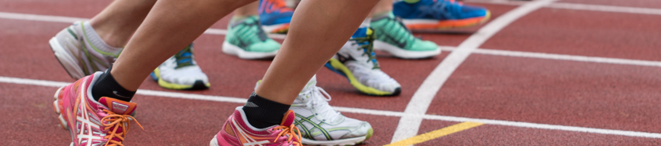 Mehrere Läufer mit bunten Sportschuhen an Startlinie