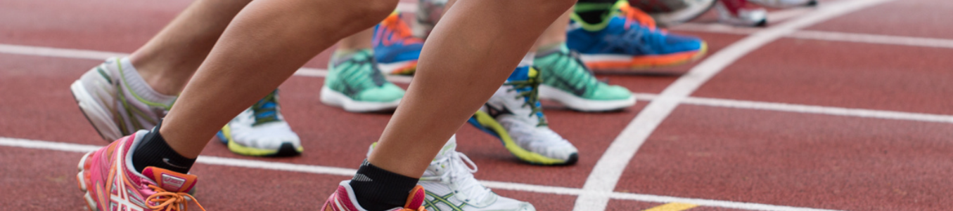 Mehrere Läufer mit bunten Sportschuhen an Startlinie