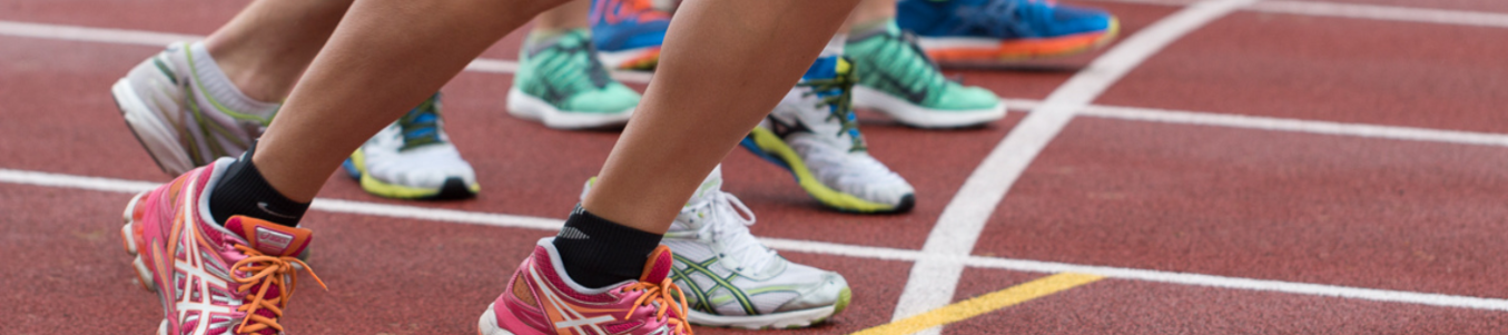 Mehrere Läufer mit bunten Sportschuhen an Startlinie