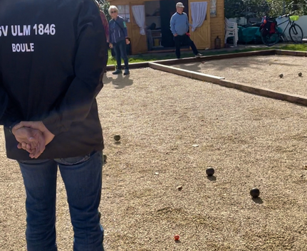 Person mit ULM 1846 BOULE Jacke auf Boulebahn