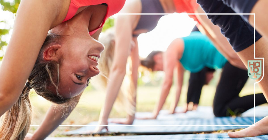 Gruppe beim Yoga im Freien in herabschauender Hund-Pose