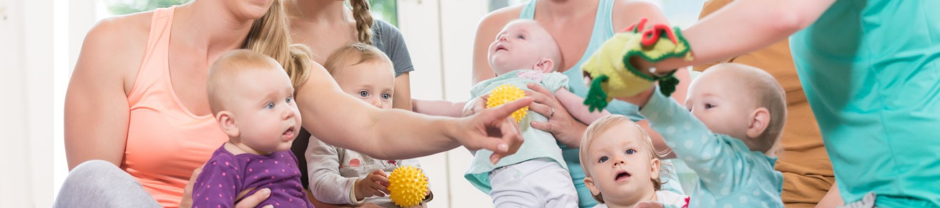 Erwachsene und Babys beim Eltern-Kind-Turnen mit Bällen